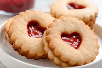 Photo of Traditional Christmas Linzer cookies with sweet jam on plate, closeup