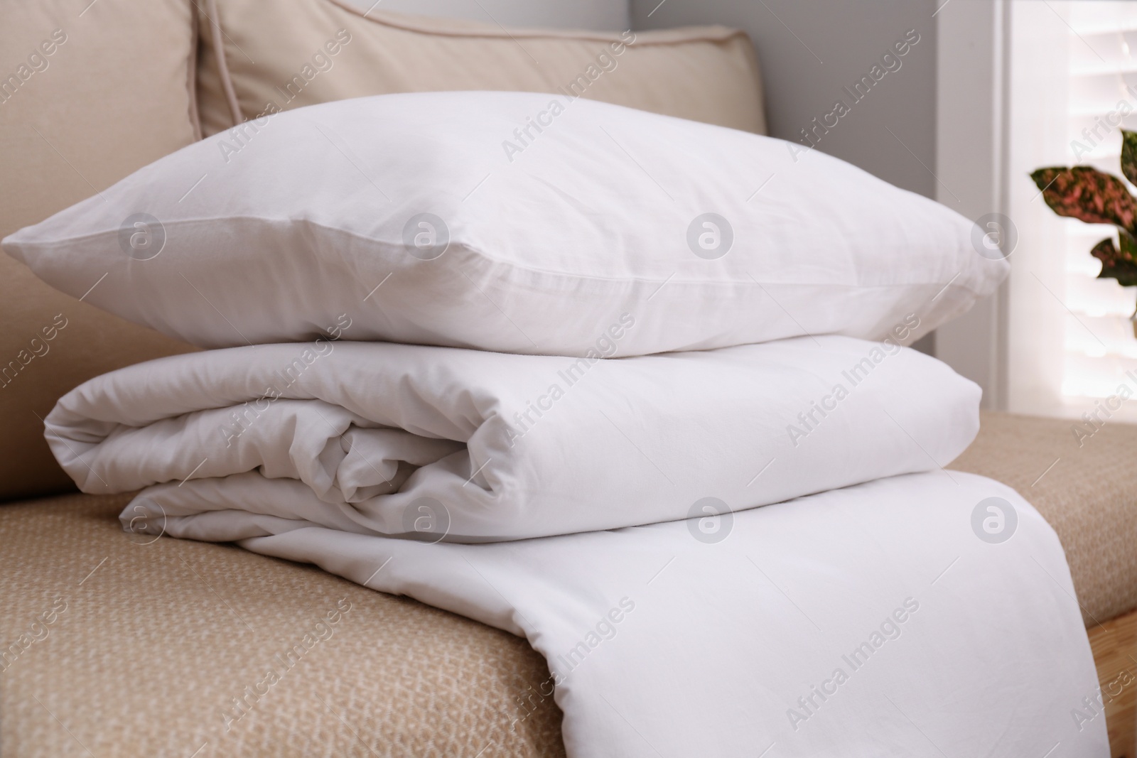 Photo of Comfortable sofa with blanket and pillow indoors, closeup