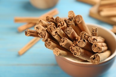 Photo of Aromatic cinnamon sticks on light blue wooden table, closeup