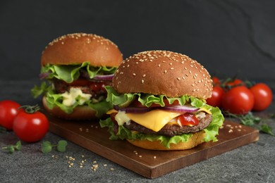 Photo of Delicious burgers with beef patty and tomatoes on grey table