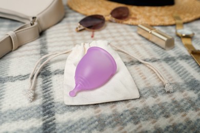 Violet menstrual cup with cotton bag on checkered fabric