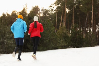 People running in winter forest, back view. Outdoors sports exercises