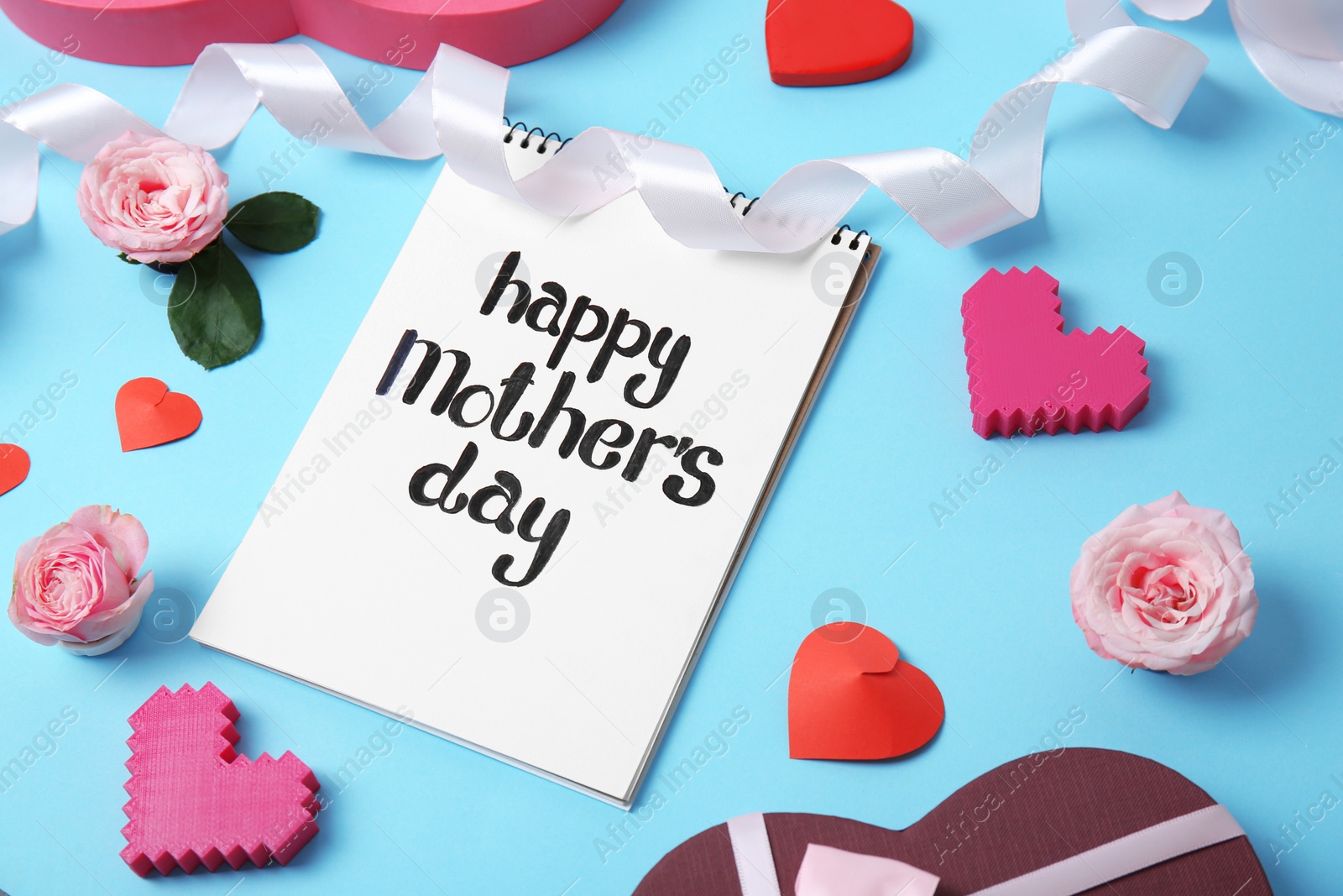 Photo of Notebook with phrase "HAPPY MOTHER'S DAY" and decor on color background