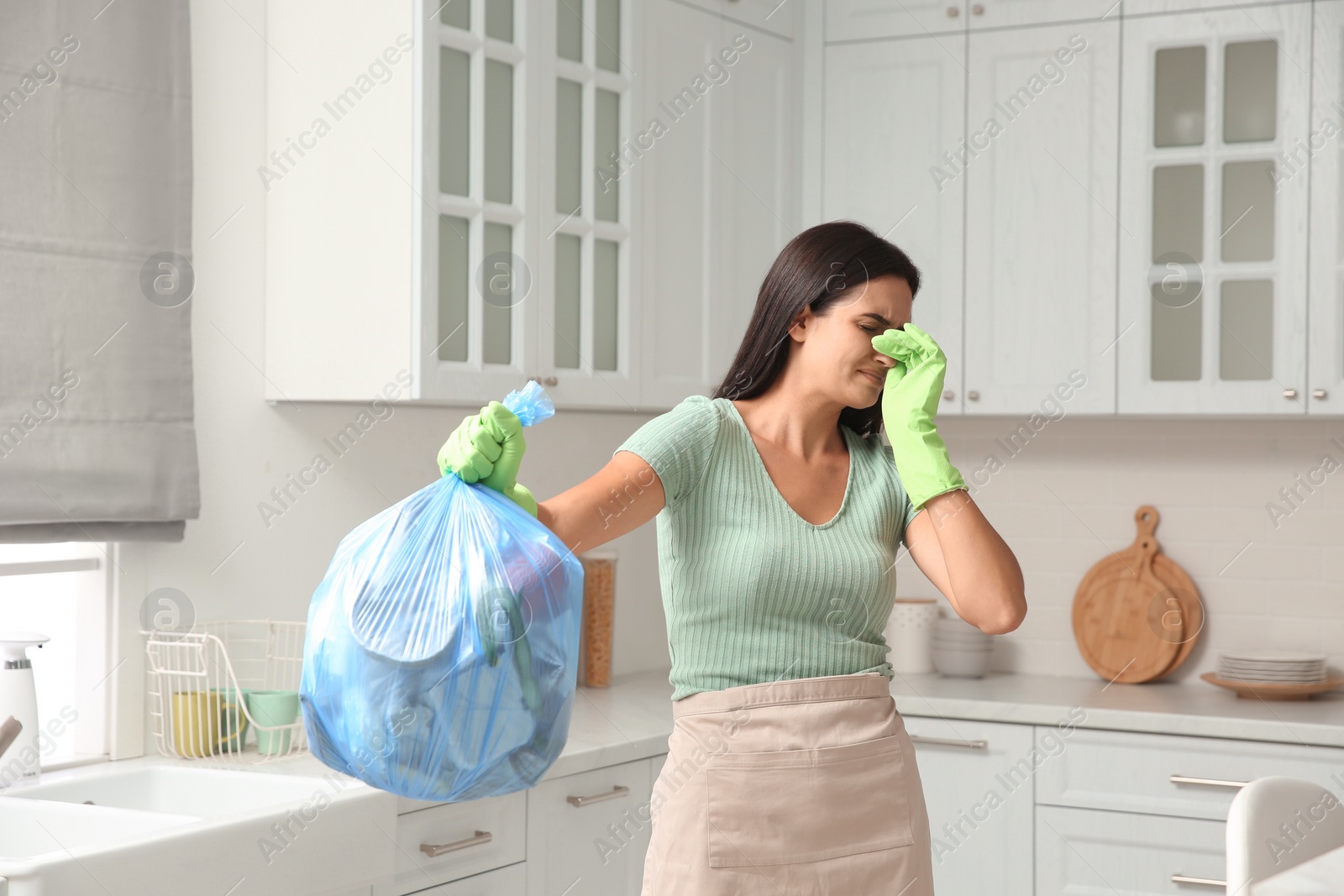 Photo of Woman holding full garbage bag at home