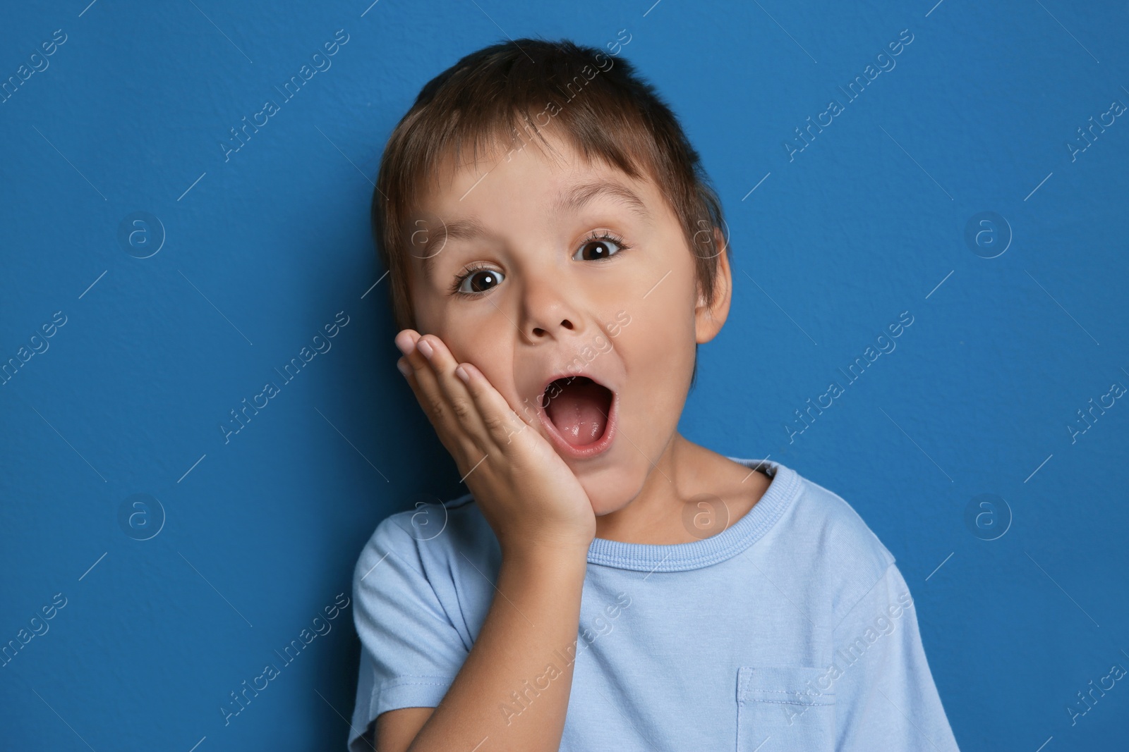 Photo of Portrait of surprised little boy on blue background