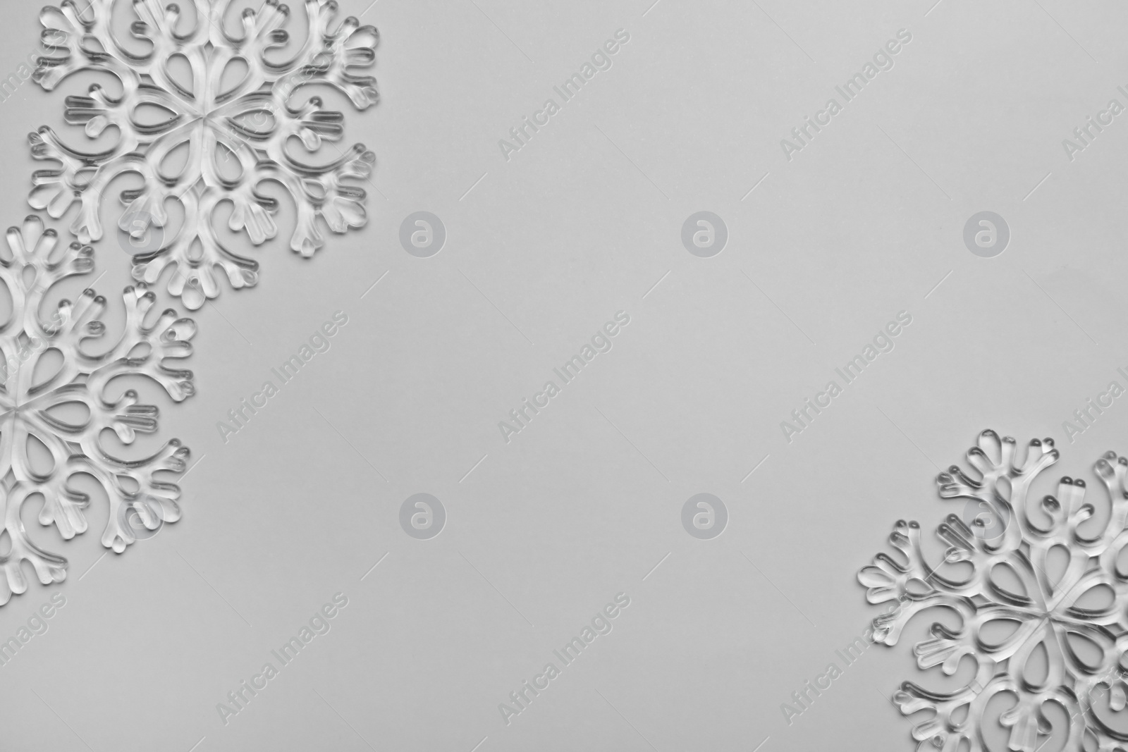 Photo of Beautiful decorative snowflakes on light grey background, flat lay. Space for text