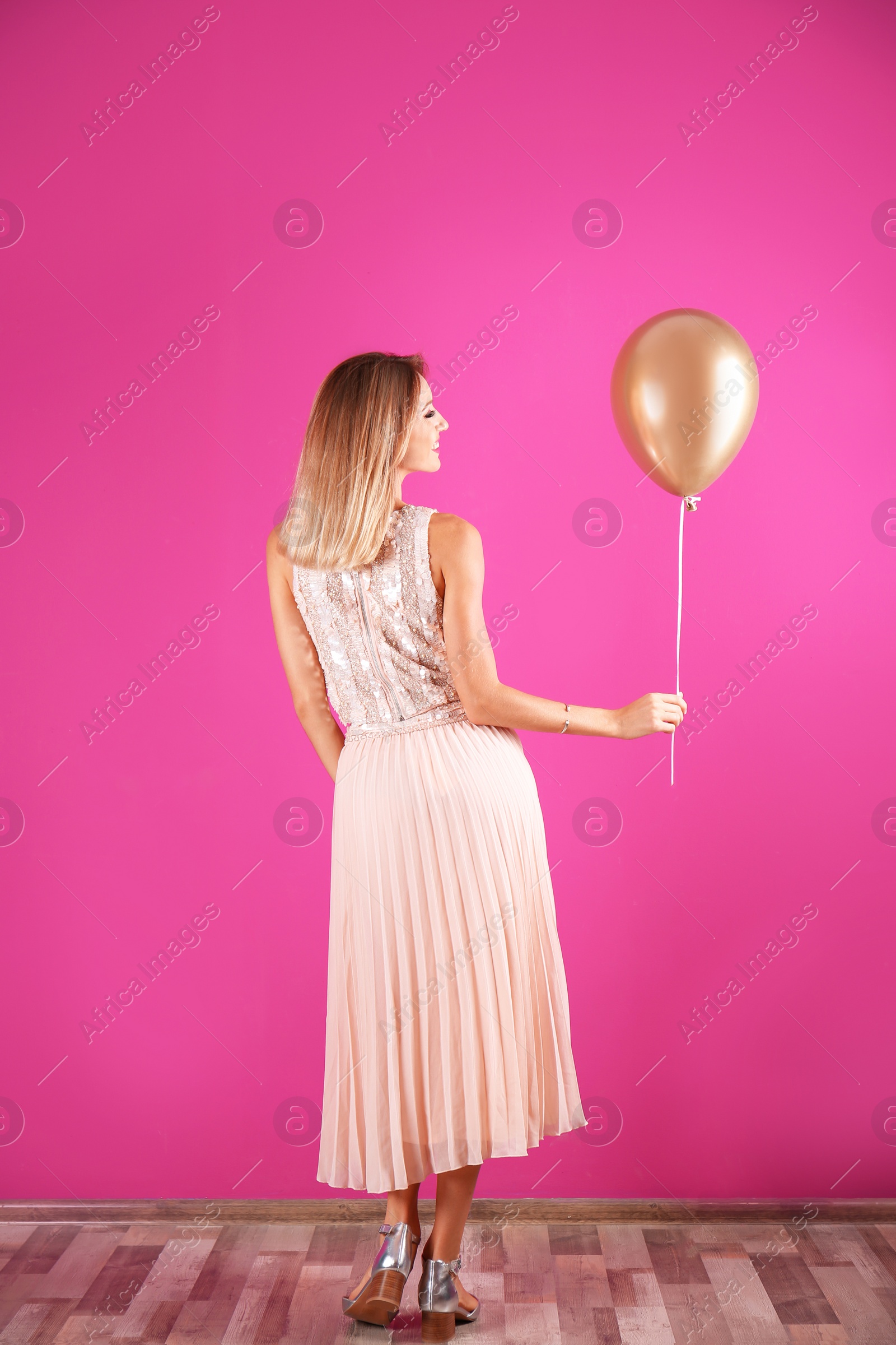 Photo of Young woman with air balloon near color wall