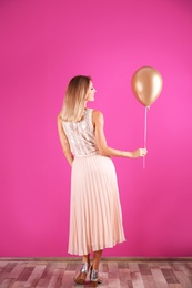 Young woman with air balloon near color wall