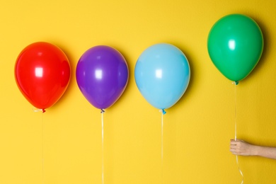 Photo of Woman holding green balloon next to others on color background. Celebration time