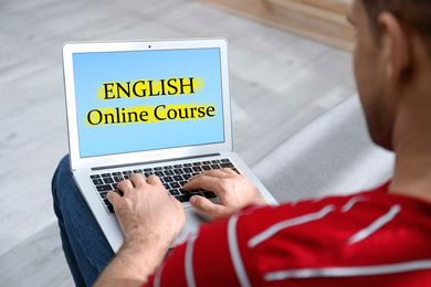 Image of Young man using laptop for online English learning at home, closeup