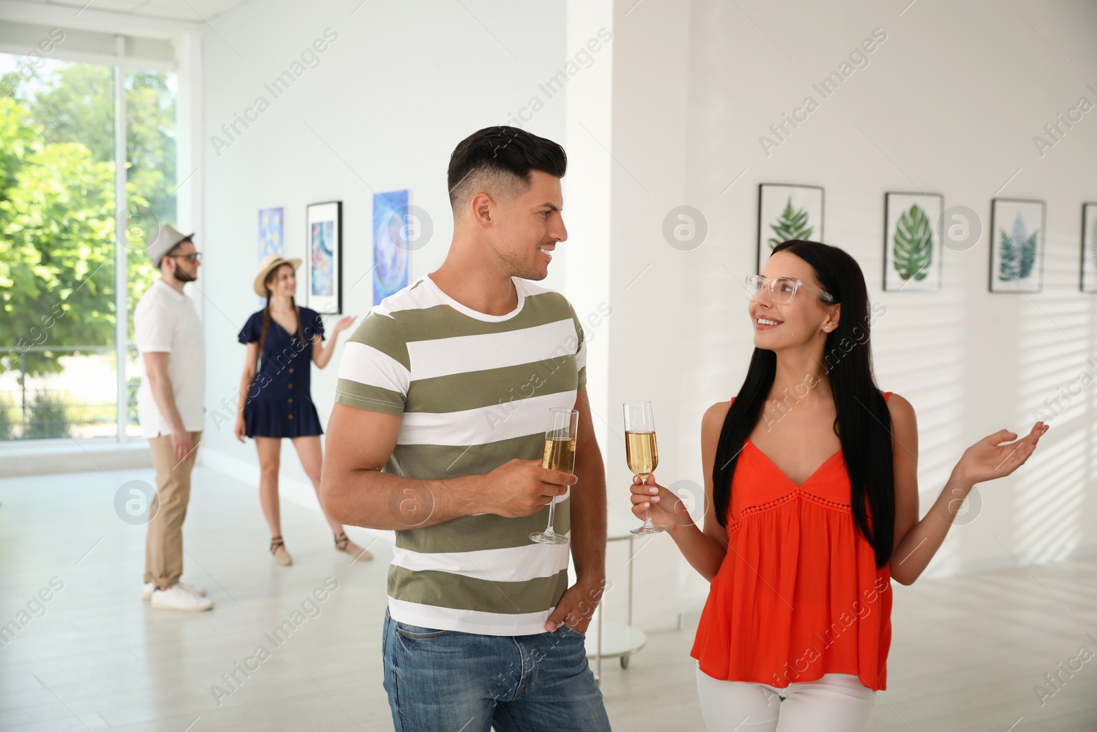 Photo of Happy couple with glasses of champagne at exhibition in art gallery