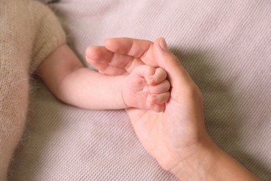 Mother and her newborn baby on light grey knitted plaid, above view