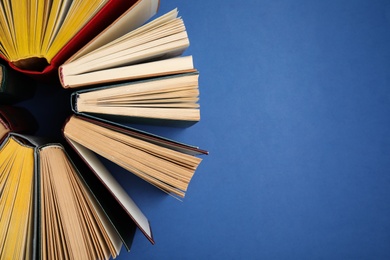 Photo of Hardcover books on blue background, flat lay. Space for text