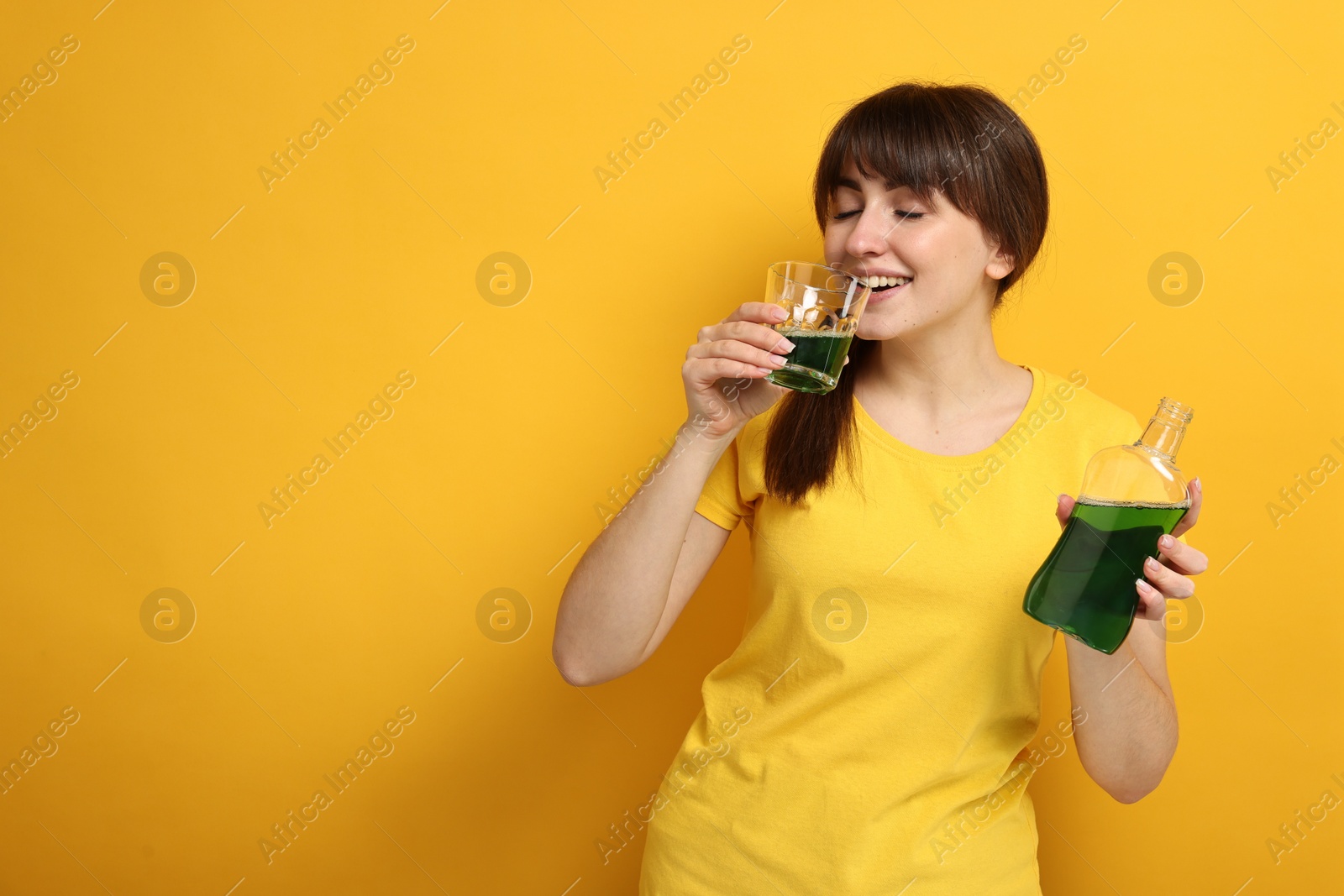 Photo of Young woman using mouthwash on yellow background, space for text