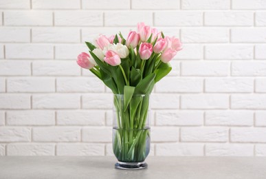 Photo of Beautiful bouquet of tulips in glass vase on light table