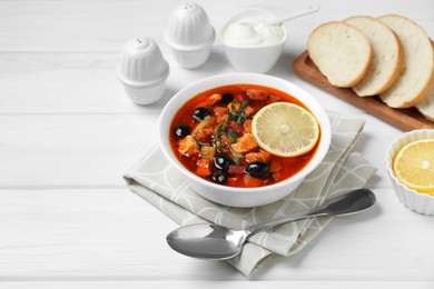 Photo of Meat solyanka soup with sausages, olives and vegetables served on white wooden table, space for text