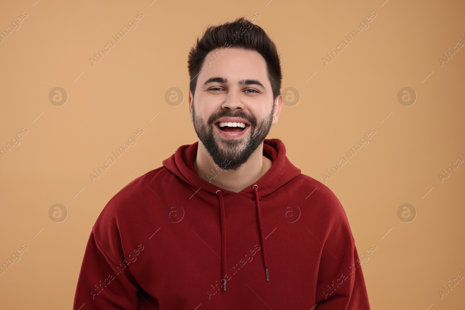 Photo of Handsome young man laughing on beige background