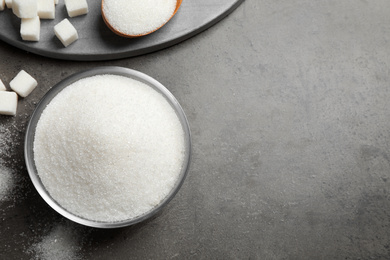 Flat lay composition with granulated sugar on grey table. Space for text