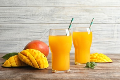 Photo of Fresh tropical mango juice and fruits on wooden table