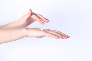 Woman applying cream on her hand against white background, closeup