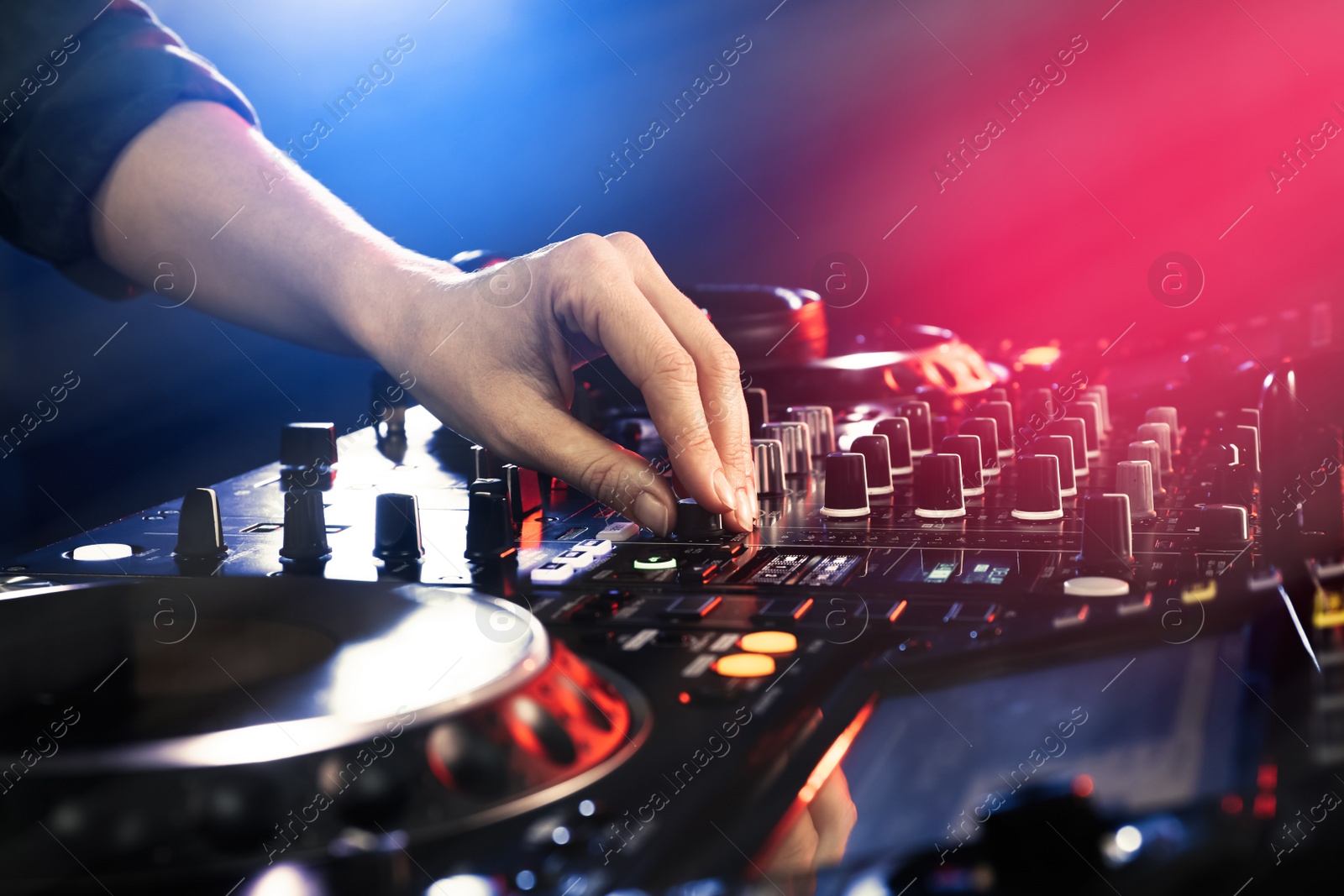 Photo of DJ creating music on modern console mixer in night club, closeup