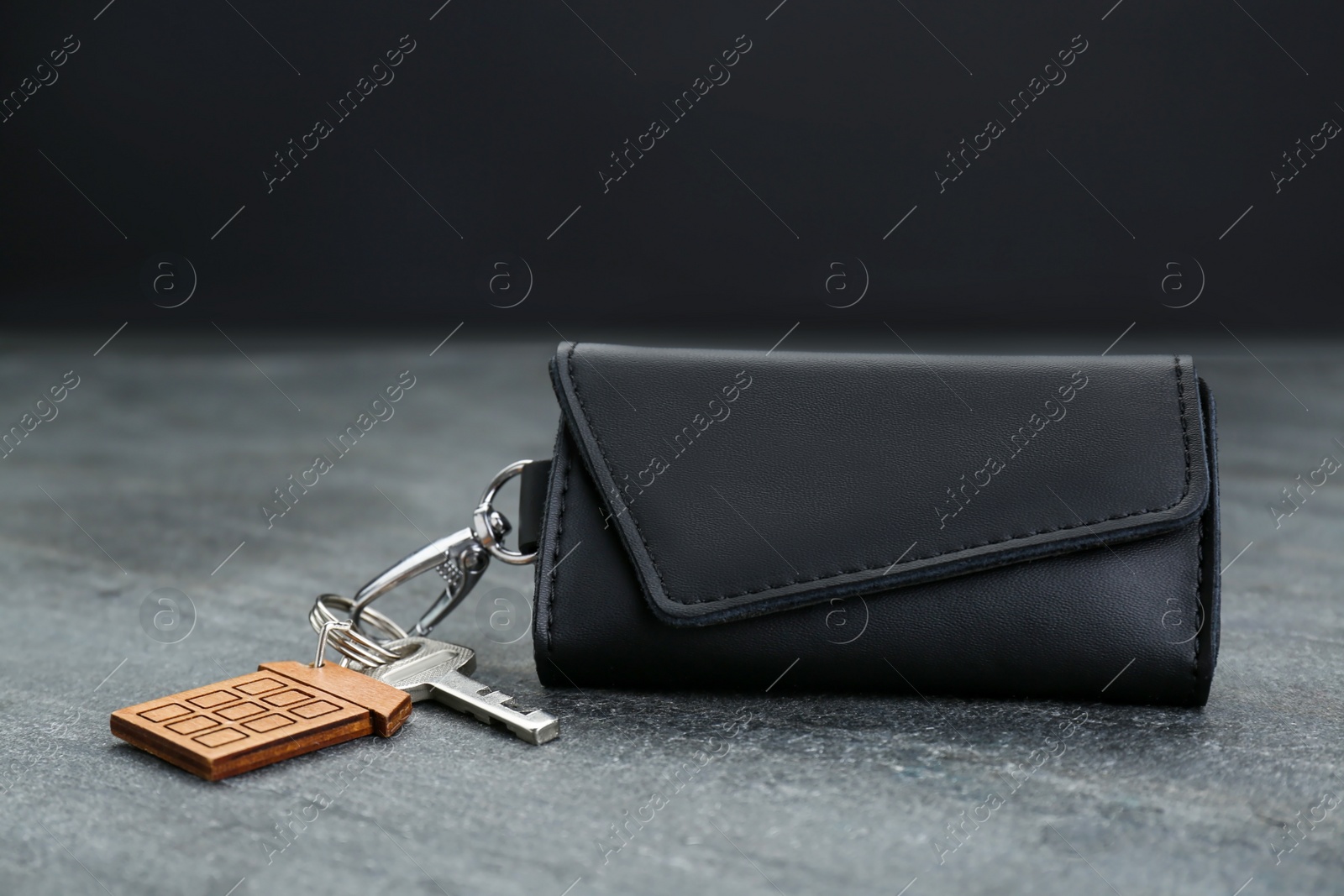 Photo of Leather case with key on grey table, closeup