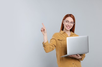 Photo of Smiling young woman with laptop on grey background, space for text