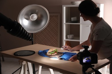 Photo of Young woman creating composition with sandwich in studio. Food photography