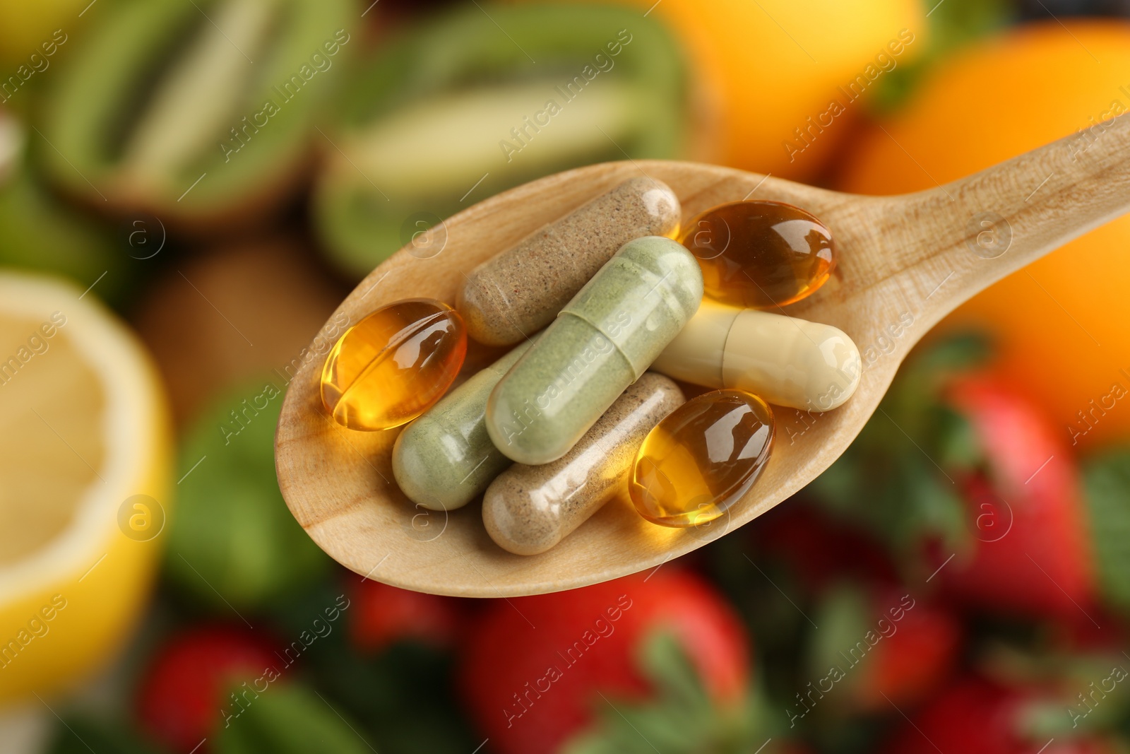 Photo of Different vitamin pills in spoon over fresh fruits, top view