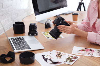 Photo of Professional photographer with camera working at table in office, closeup