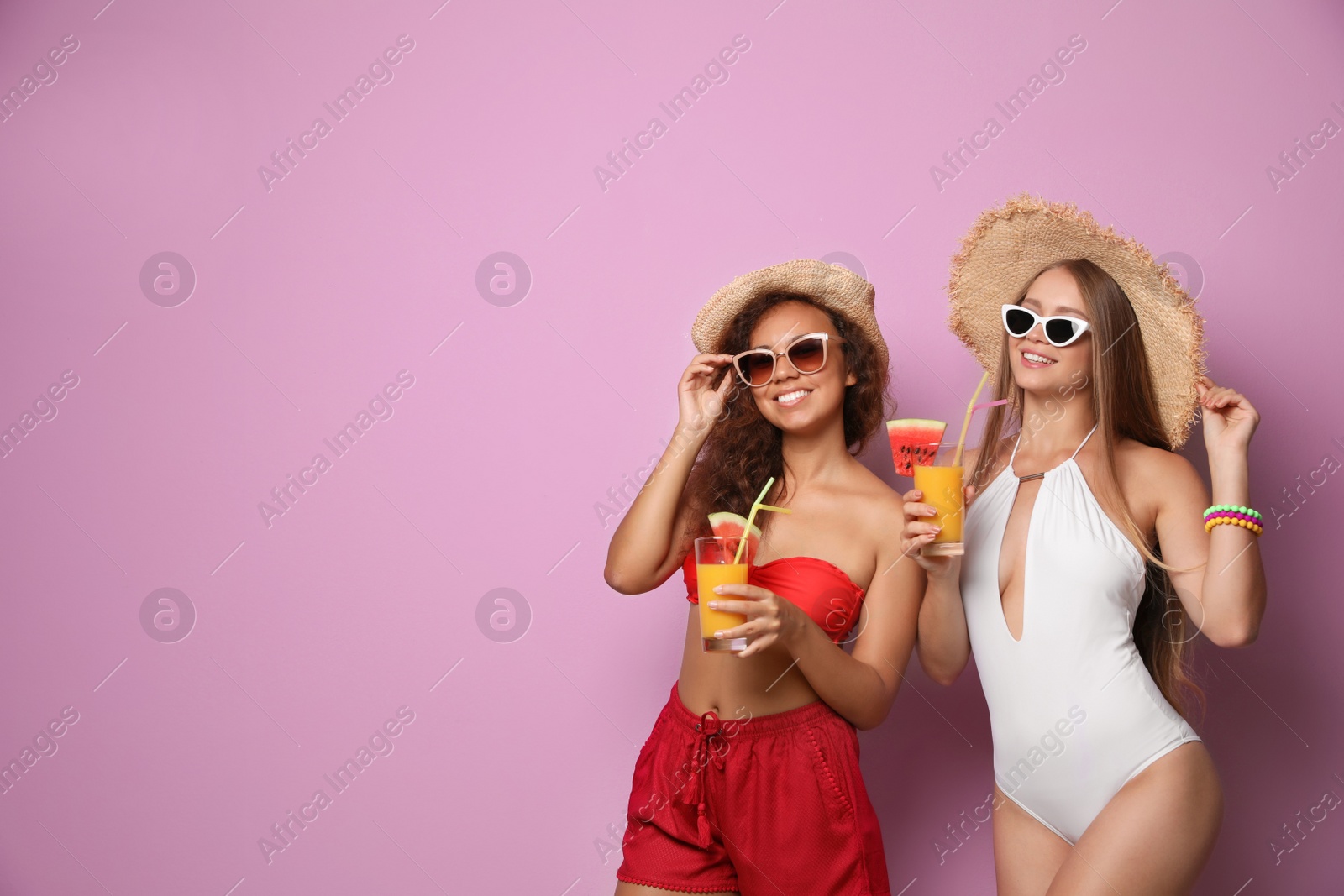 Photo of Beautiful young women in beachwear with cocktails on color background. Space for text
