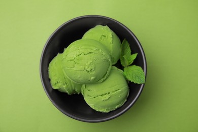 Photo of Tasty matcha ice cream in bowl on green table, top view