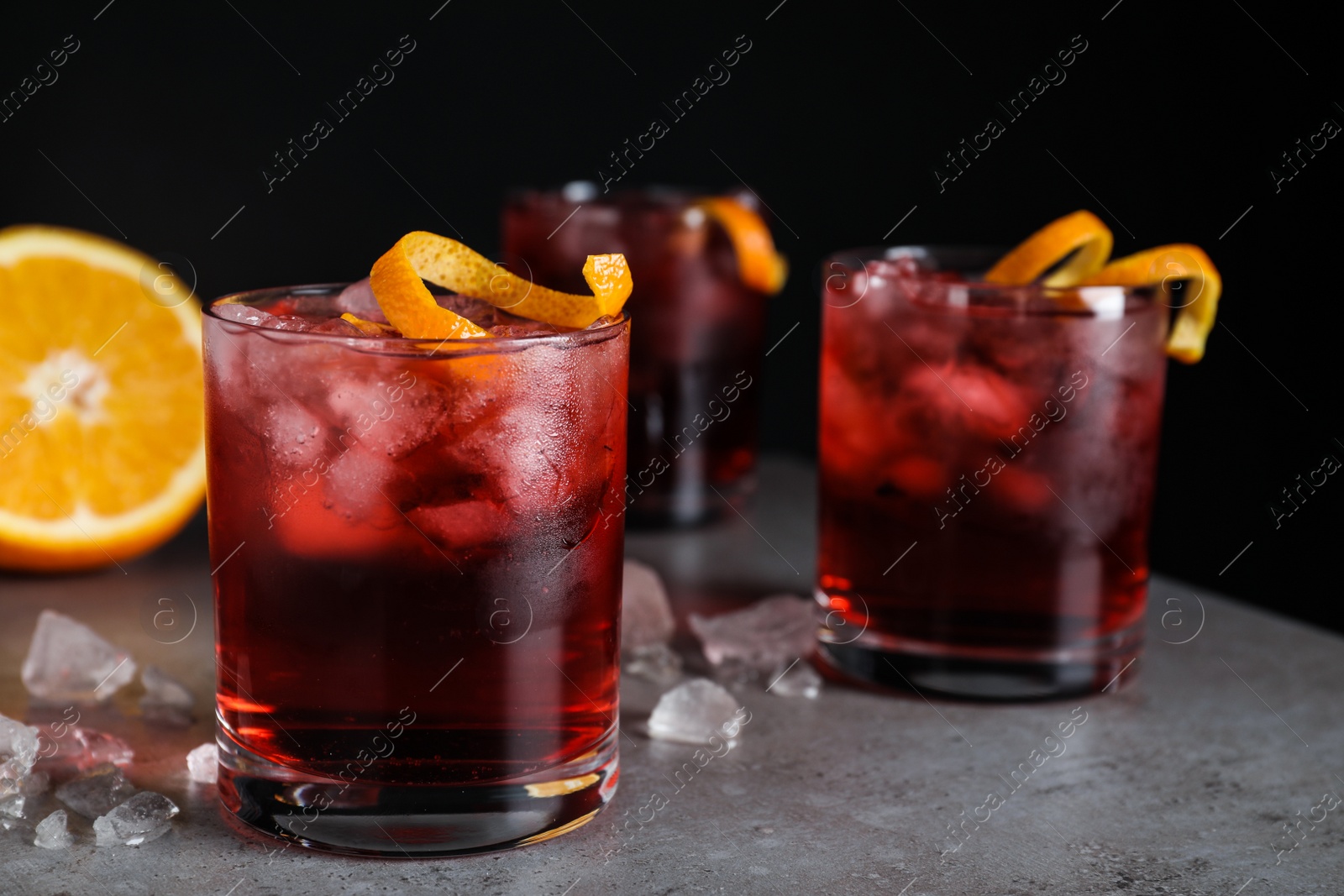 Photo of Fresh Negroni cocktails with orange zest on grey table