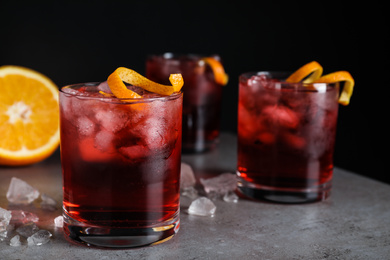Fresh Negroni cocktails with orange zest on grey table