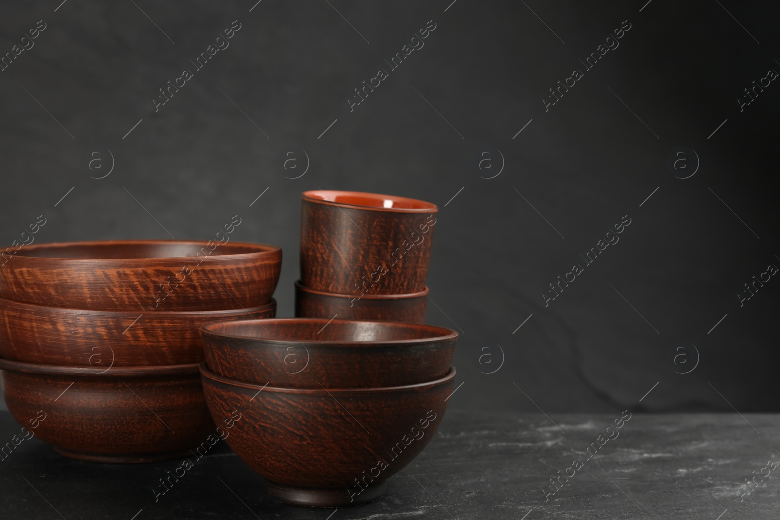 Photo of Set of clay utensils on black table. Space for text