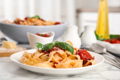 Photo of Tasty pasta with cheese, tomato sauce and basil on white marble table