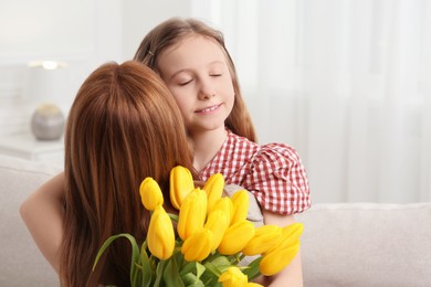 Photo of Daughter congratulating mom with bouquet of yellow tulips at home, space for text