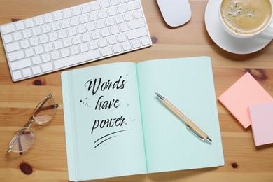 Open notebook with phrase Words Have Power and pen on wooden table, flat lay. Workplace with cup of coffee