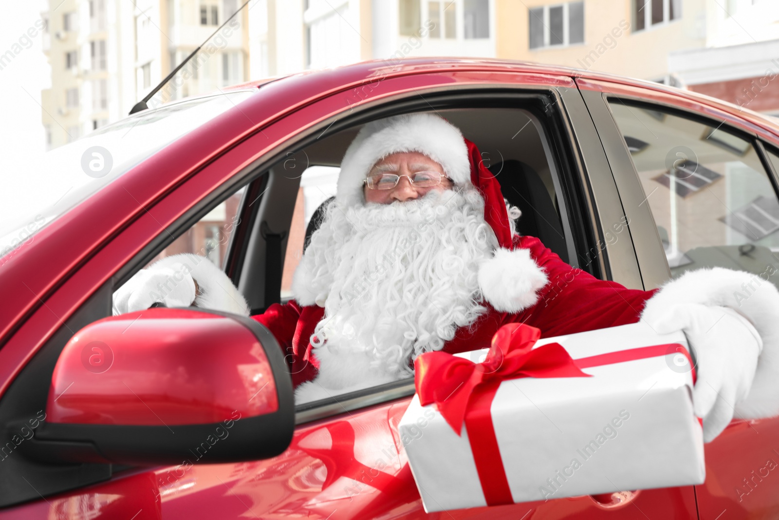 Photo of Authentic Santa Claus with gift box driving car, view from outside