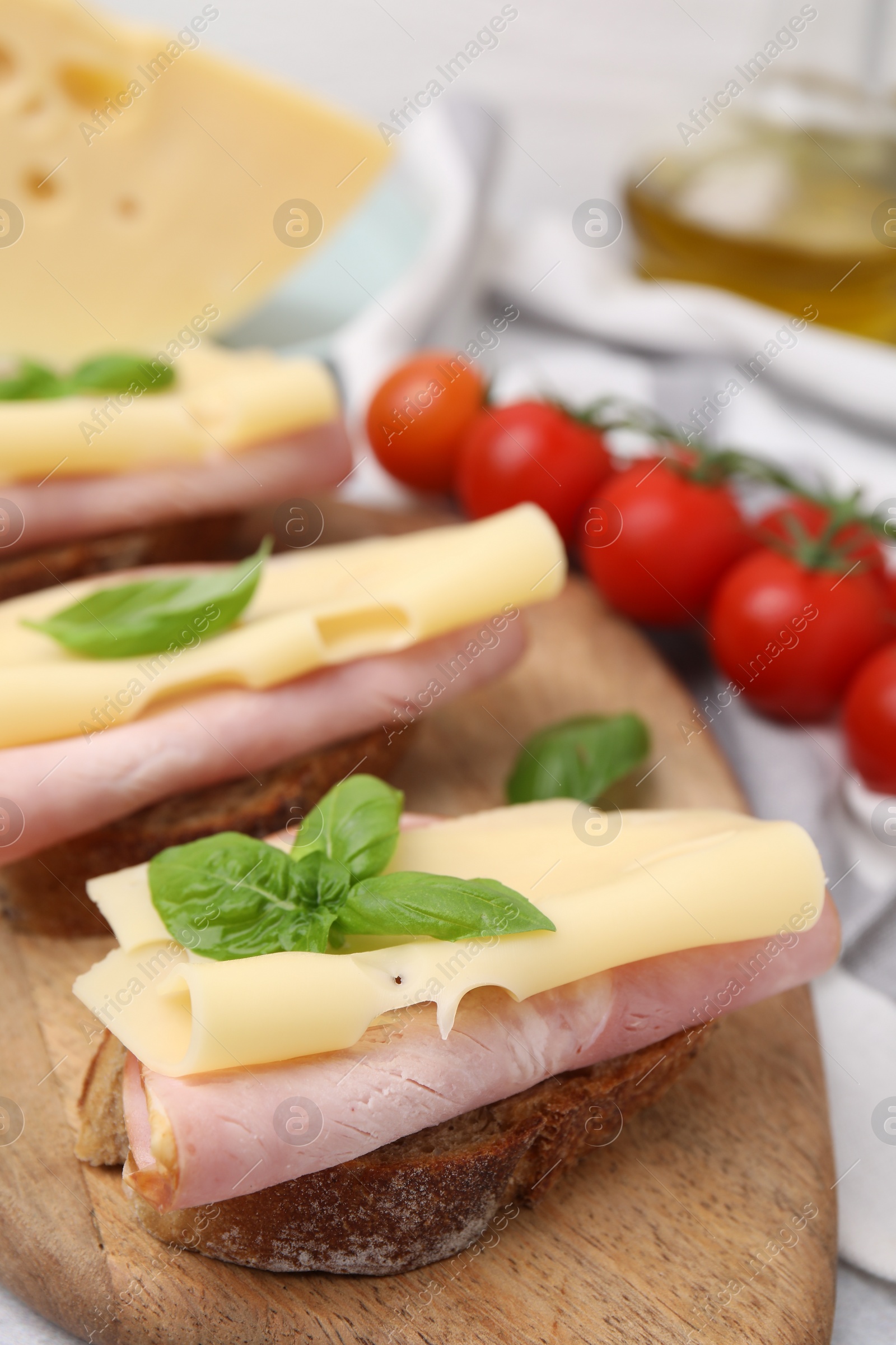Photo of Delicious sandwiches with ham and cheese on wooden board, closeup