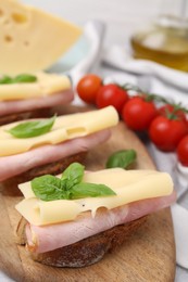 Photo of Delicious sandwiches with ham and cheese on wooden board, closeup