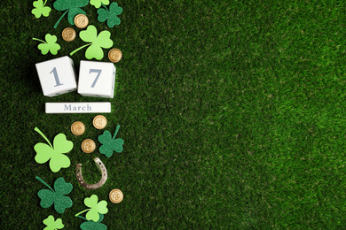 Photo of Flat lay composition with horseshoe and wooden block calendar on grass, space for text. St. Patrick's Day celebration