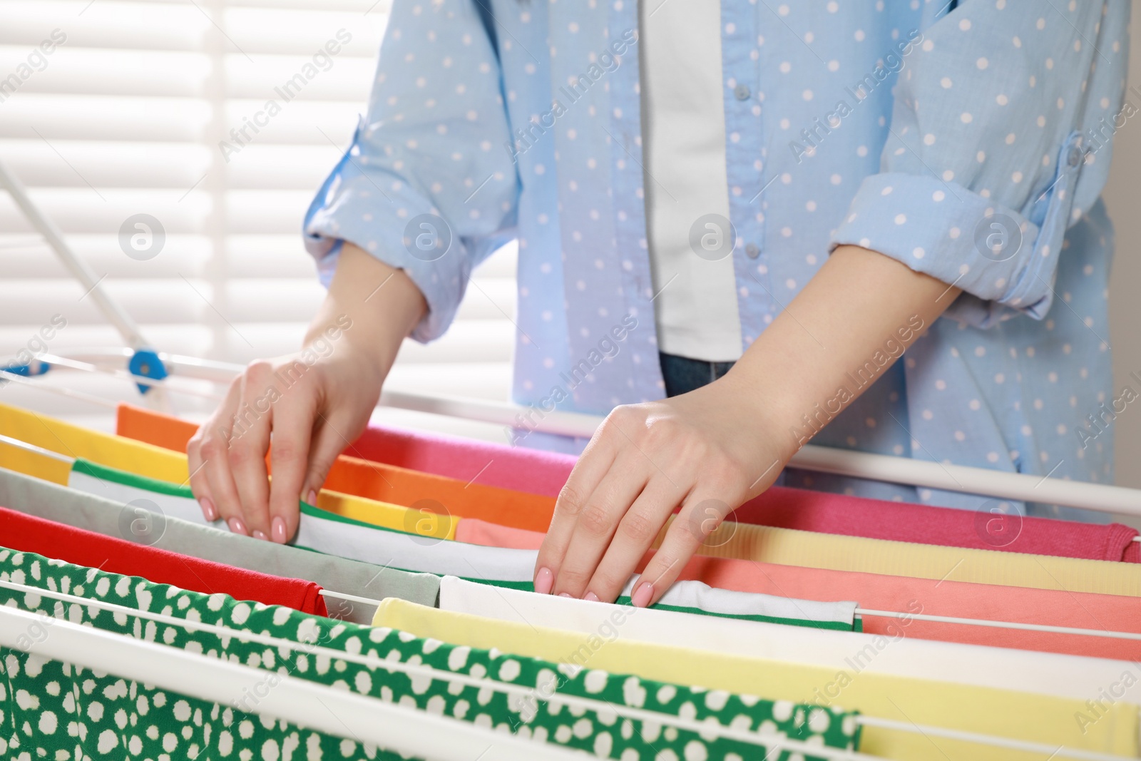 Photo of Woman hanging different apparel on clothes airer, closeup