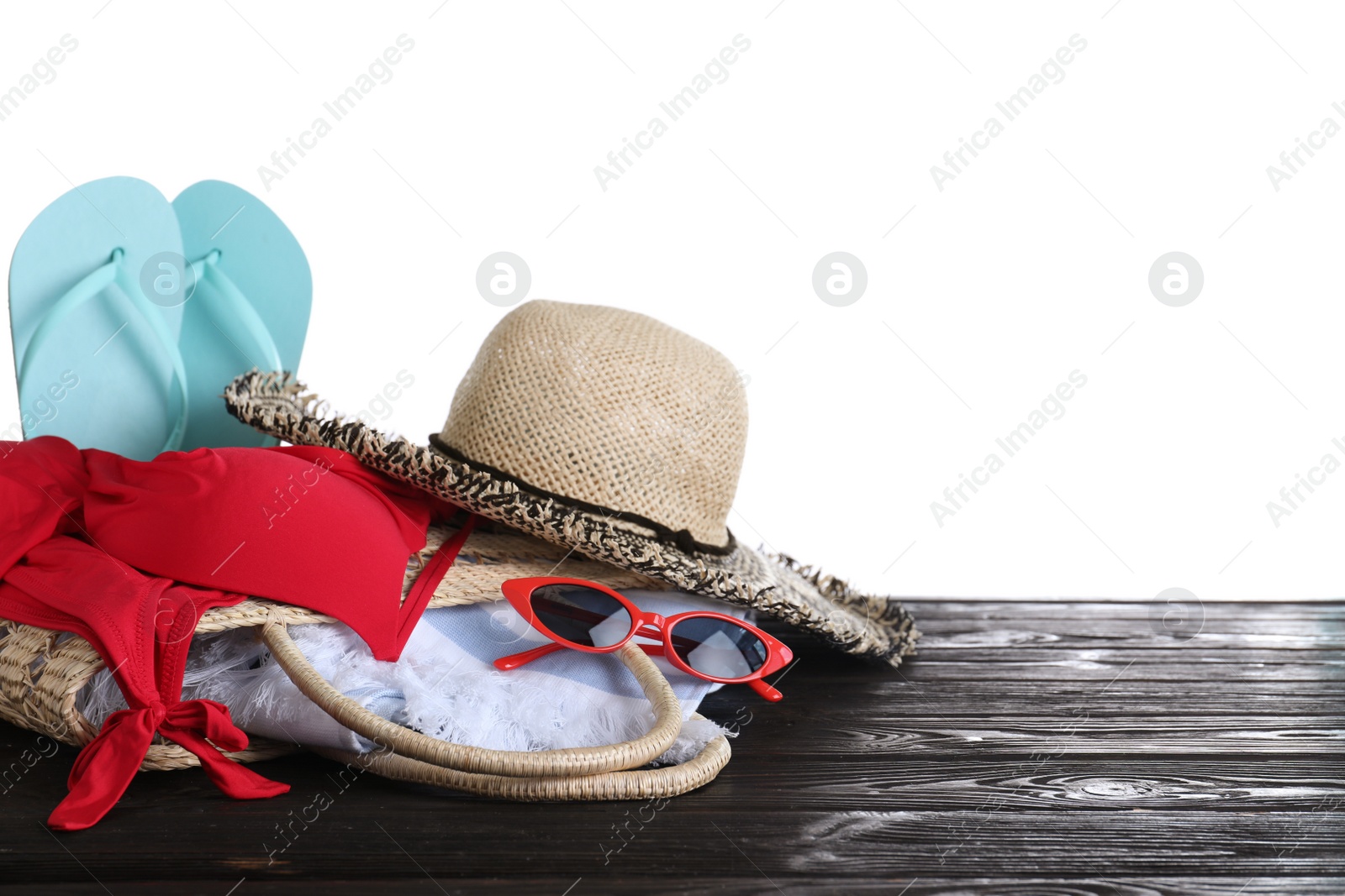 Photo of Different beach objects on black wooden table against white background. Space for text