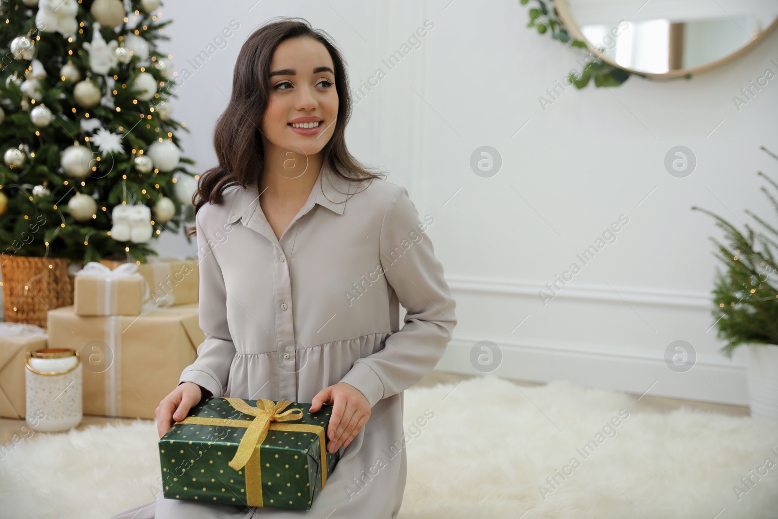 Photo of Woman with gift box on floor at home. Space for text