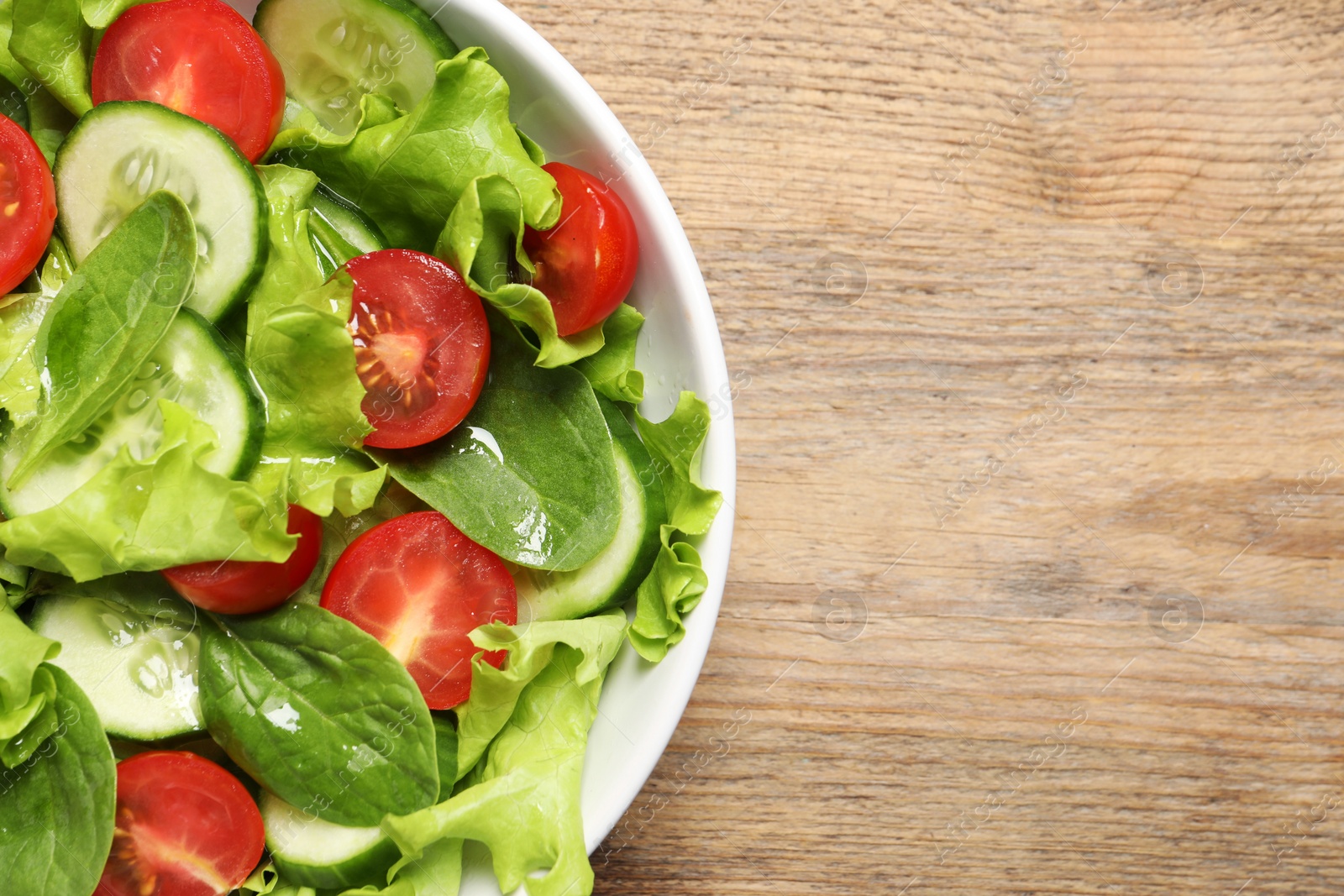 Photo of Delicious vegetable salad on wooden table, top view. Space for text