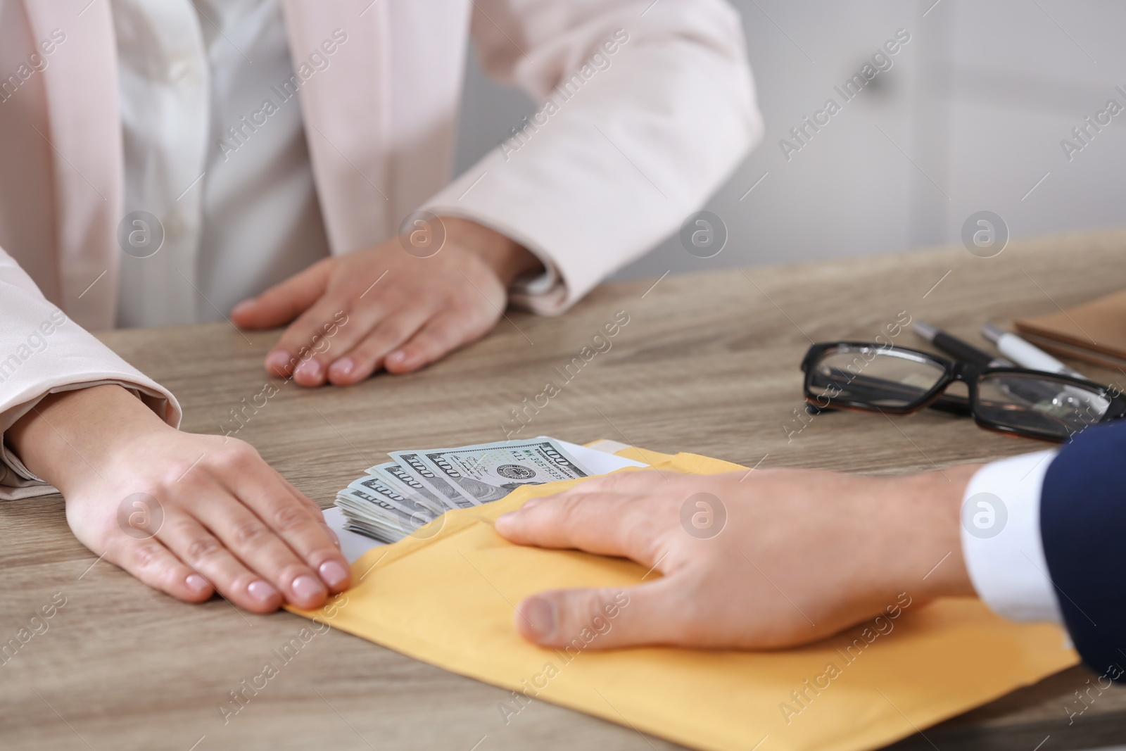 Photo of Man giving bribe to woman at table in office, closeup