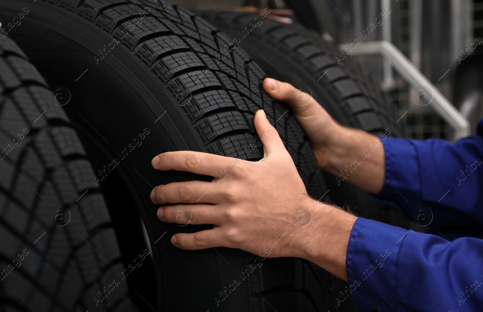 Photo of Male mechanic with car tire in auto store, closeup