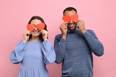 Photo of Lovely couple with paper hearts on red background. Valentine's day celebration