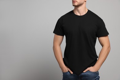 Photo of Man wearing black t-shirt on light grey background, closeup. Mockup for design